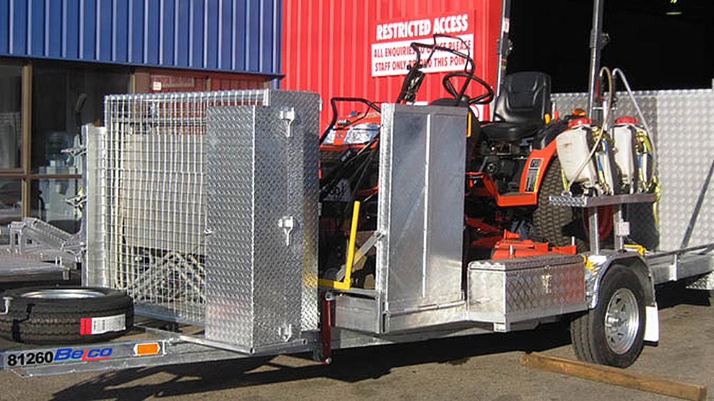 Lawn mower trailer loaded with mowers and spraying equipment.